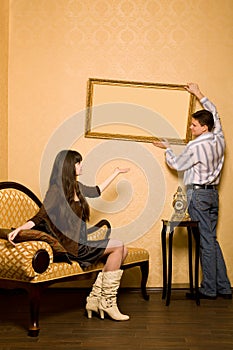 Woman on sofa and man hang up on wall picture