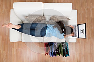 Woman On Sofa Shopping Online With Laptop