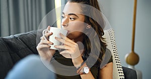 Woman, sofa and thinking with coffee, home and relax with happy memory, vision and peace in living room. Girl, tea cup
