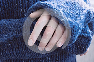 Woman in soft warm dark blue knitted sweater folded her hands