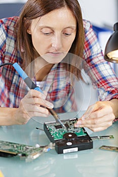 woman soldering circuit board in tech office