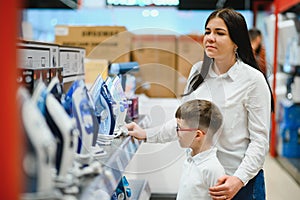 Woman with son choosing electric iron in electronics store