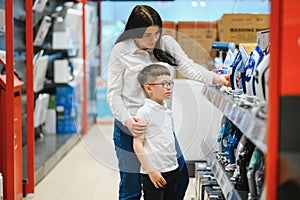 Woman with son choosing electric iron in electronics store