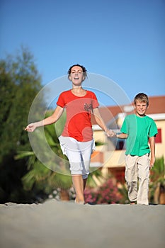 Woman with son holding on to hands hurry on beach