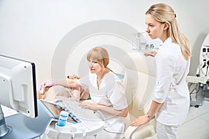 Woman sonographer performing ultrasound of the thyroid glands to woman