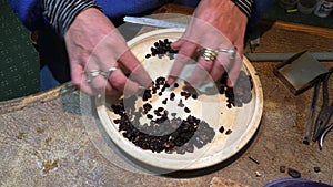 Woman sorting and valuing raw garnet gemstones