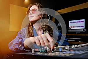 Woman sound engineer at the mixing Board. The girl at the remote in the recording Studio. Professional recording of musicians in