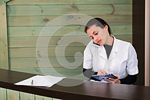 Woman in a spa recpetion uses tablet pc texting to client. Beauty and technology concept.