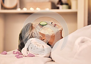 Woman, spa and relax with face mask, cucumber and skincare treatment at beauty salon. Calm mature female client cooling