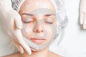 Woman in spa salon receiving face treatment with facial cream