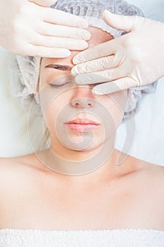 Woman in spa salon receiving face treatment with facial cream