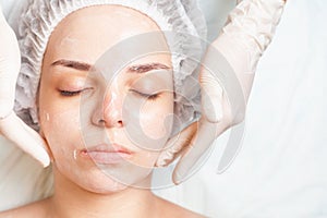 Woman in spa salon receiving face treatment with facial cream