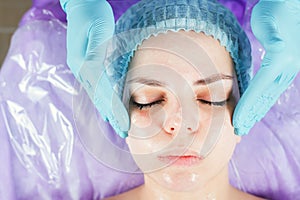 Woman in spa salon receiving face treatment with facial cream