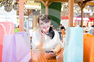 Woman speak phone with her shopping bag and credit card in the restaurant