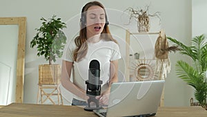 Woman speaking into a microphone in a recording studio smiles while creating a podcast for an Internet blog.