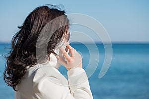 Woman is speaking by mobile phone at the seaside