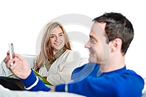 Woman speaking to man playing on his phone