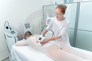 Woman in special white suit getting anti cellulite massage in a spa salon. LPG, and body contouring treatment in clinic.