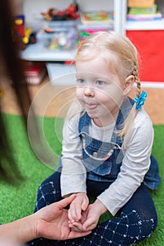 Woman speech therapist helps cute girl to learn correct pronunciation and literate speech