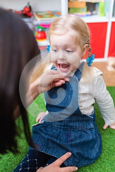 Woman speech therapist helps cute girl to learn correct pronunciation and literate speech