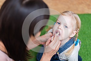 Woman speech therapist helps cute girl to learn correct pronunciation and literate speech