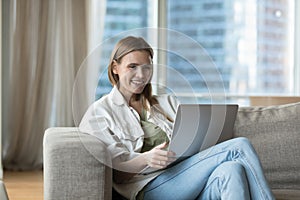 Woman spend time on internet sit on sofa with laptop
