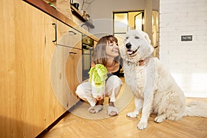 Woman spends leisure time dog while cooking healthy food in kitchen