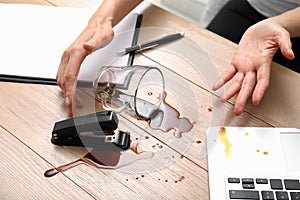 Woman spilled coffee on wooden office desk, closeup