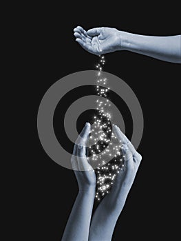 Woman spilling out of hand to other hands bright sparkly stars on black background