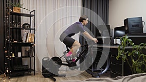 Woman is spinning pedals on stationary bicycle. Cyclist is training on smart cycling trainer