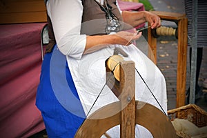 Woman spinning sheep wool thread by hand. Hands of a woman demonstrating traditional wool spinning on an old spinning wheel