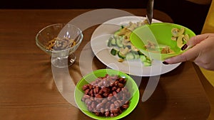 A woman spooning mushrooms in a salad bowl