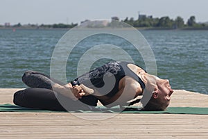 Woman with sport bra doing yoga fitness exercise for relax and healthy at lake in morning, Nature background, Concept outdoor