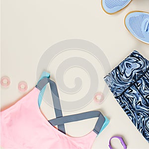 Woman sport bra, leggins, sneakers, headphones and fitness tracker on neutral background. Sport fashion concept.