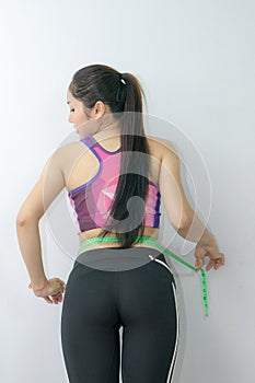 Woman in sport bra measuring her body with tape isolated on whit
