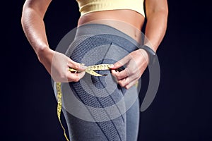 Woman in sport clothes measusing her buttock. Fitness and healthcare concept