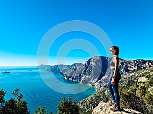 Woman in sport outfit enjoying scenic view from hiking trail between Positano and Praiano at the Amalfi Coast, Italy, Europe