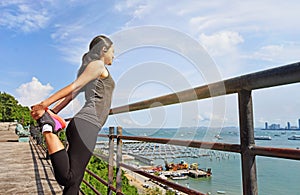 Woman in sport outfit warming up on pier near water