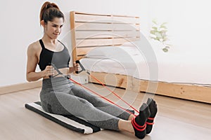 Woman in sport wears do Resistance Band Seated Pronated Row in her room.