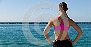 Woman in sports bra looking at the ocean