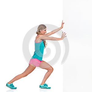 Woman In Sports Clothes Pushing White Wall