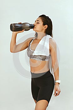 Woman in sports clothing drinking water after workout