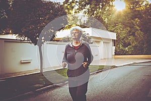 Woman in sports clothing jogging in city park.