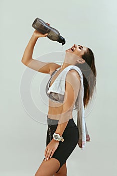 Woman in sports clothing pouring water on body after workout