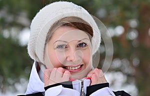 Woman in sports jacket and hat at winter pine forest