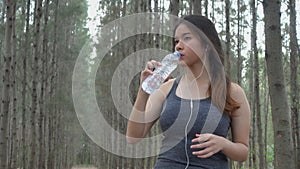 Woman in sports while listening to music athlete takes a break drink water from a plastic bottle