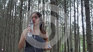 Woman in sports while listening to music athlete takes a break drink water from a plastic bottle