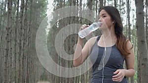 Woman in sports while listening to music athlete takes a break drink water from a plastic bottle