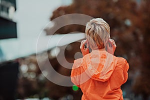 a woman in a sports outfit is resting in a city environment after a hard morning workout while using noiseless