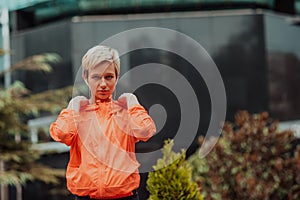 a woman in a sports outfit is resting in a city environment after a hard morning workout while using noiseless